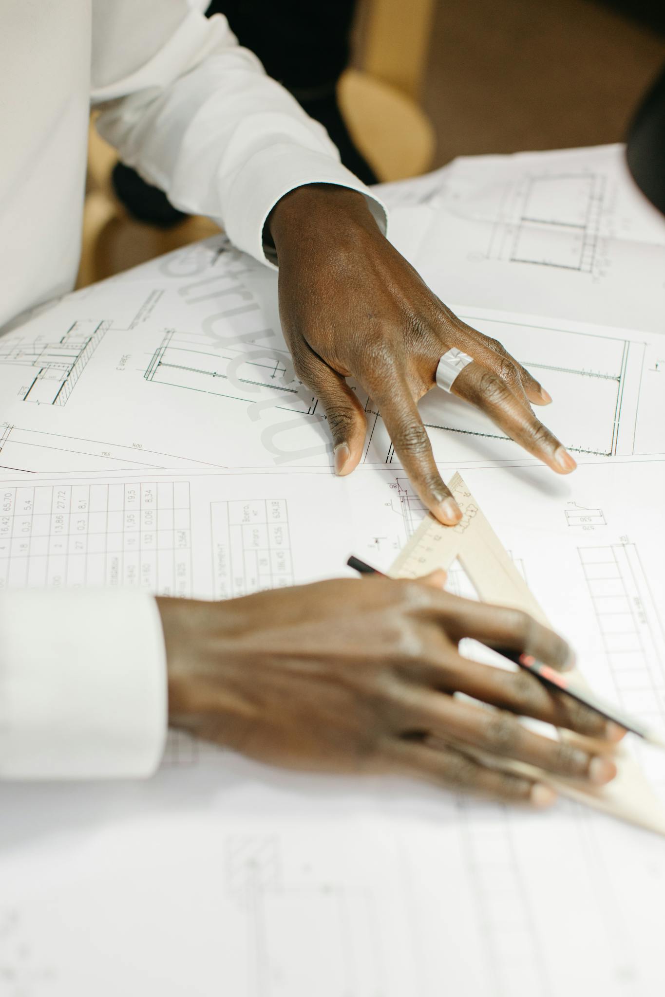 Close-up of a person drafting architectural plans with precision tools.