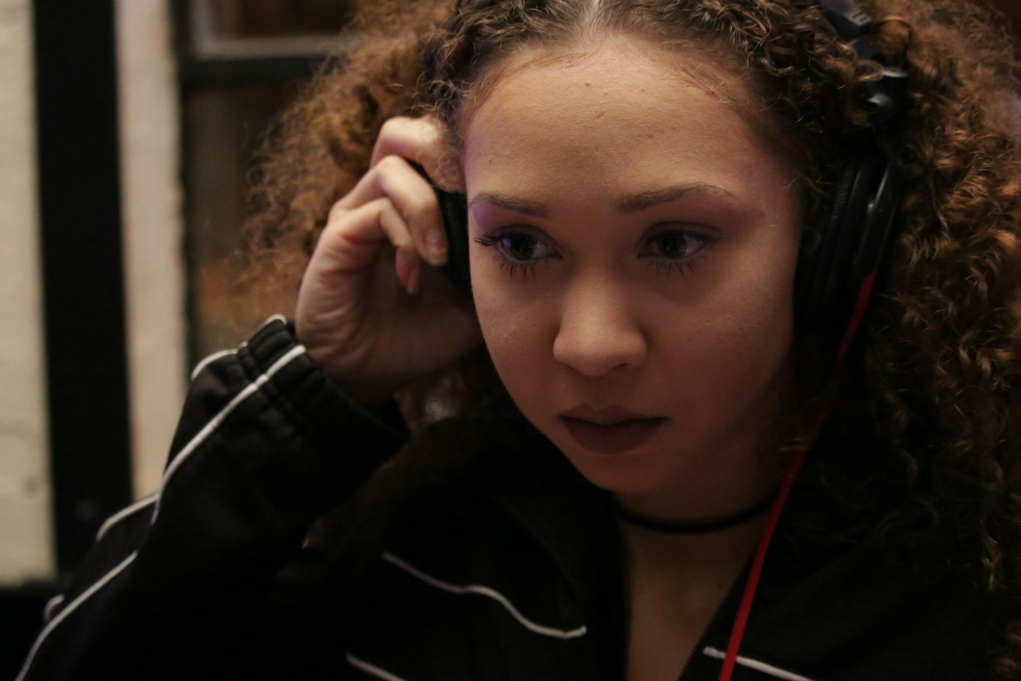 Woman intently listening through headphones, showcasing concentration and focus.